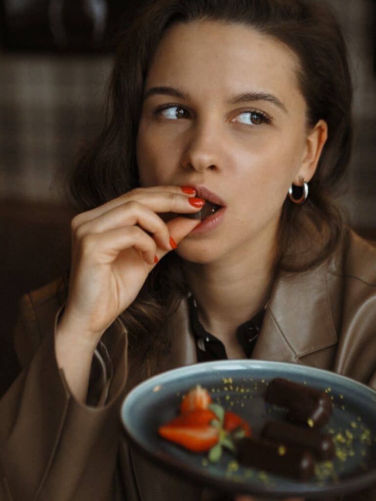 A Woman in a Leather Jacket Eating Chocolate