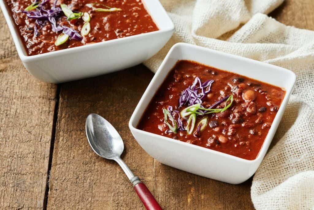 Savory Chocolate Recipes, two bowls of chili and a spoon on a wooden table