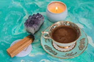 Teacup containing hot chocolate next to a candle and crystal